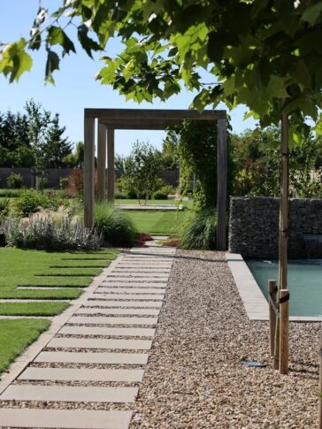 Jardín con piscina y camino de grava estabilizada en un patio de verano